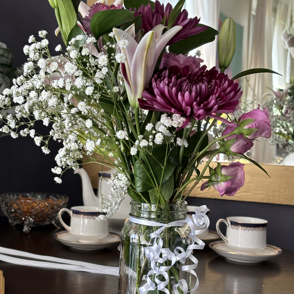 A bouquet in a glass jar beside a teacup