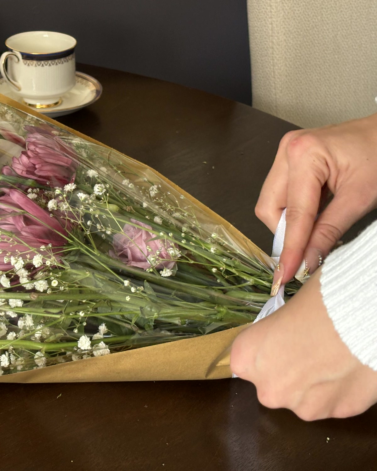Folding kraft paper around a bouquet of pink roses and baby's breath